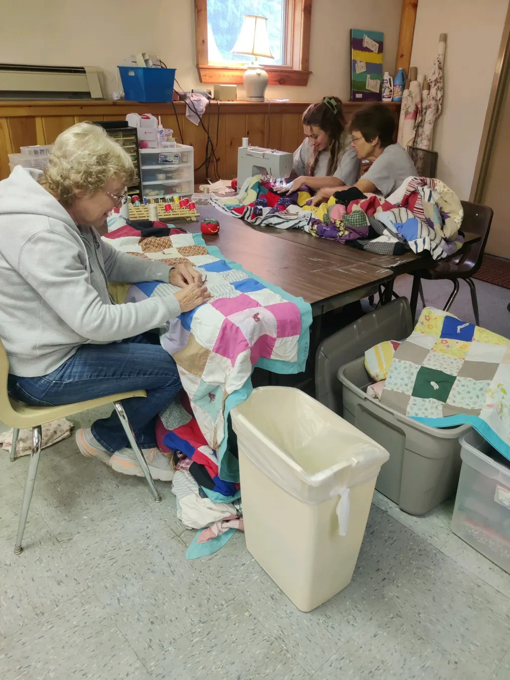 The ladies from West Shore Free Church helping Emma, a Resident, sew quilts
