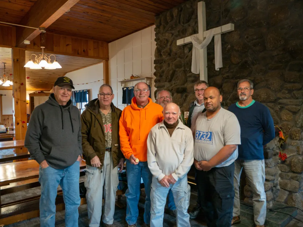 group of eight men ages fifty to seventy-five stand smiling for a picture